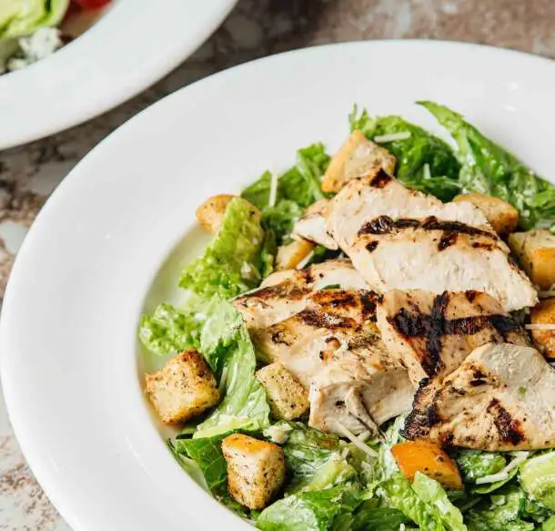 Sliced grilled chicken on Caesar salad with croutons