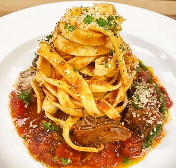 Ribbon pasta piled over braised beef in tomato sauce, topped with parmesan and parsley