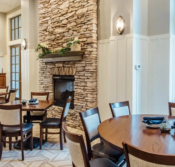 Wooden dining tables set beside a tall stacked-stone fireplace