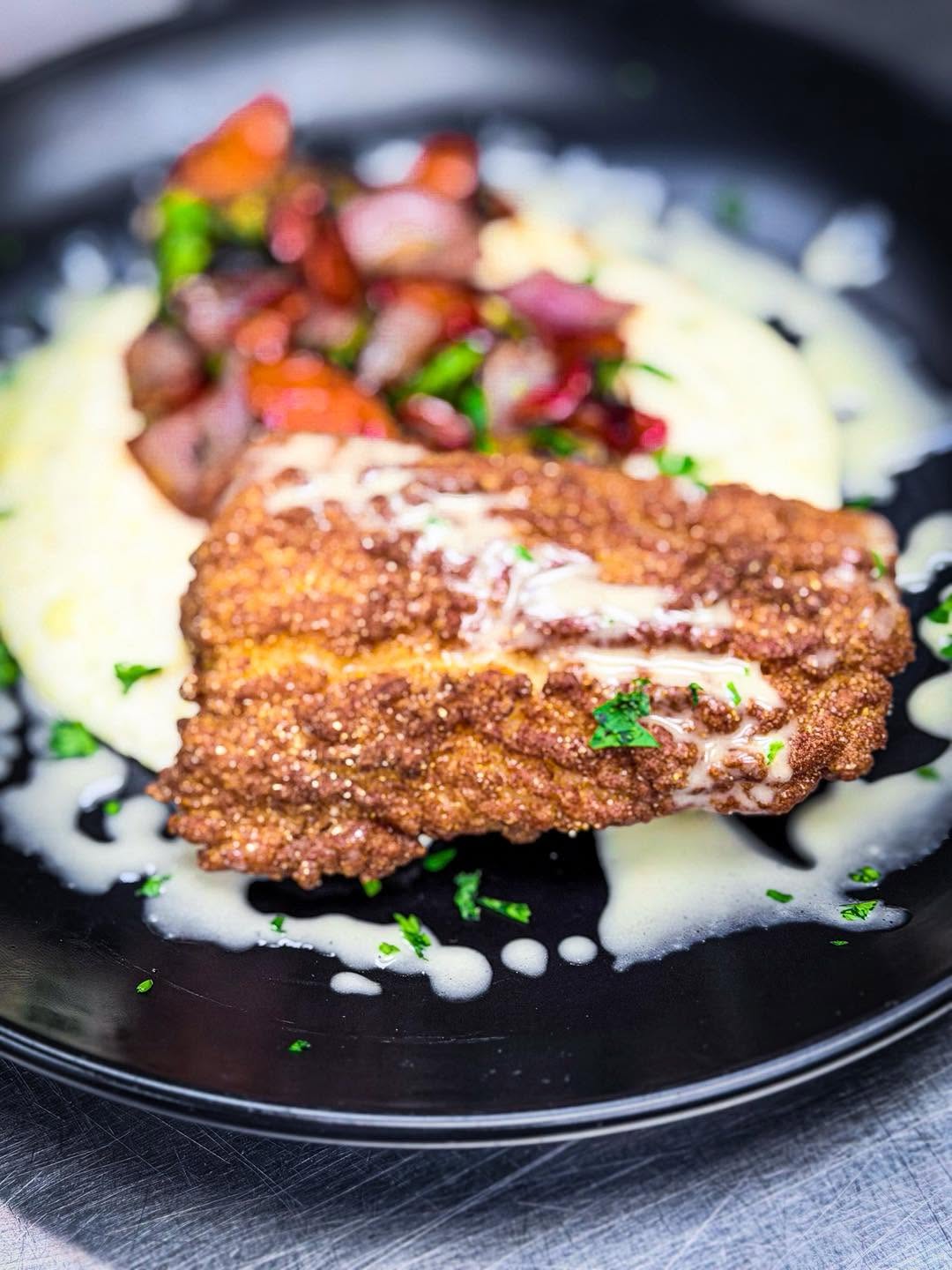 Crisp cornmeal-coated fish over creamy grits with butter sauce and roasted vegetables