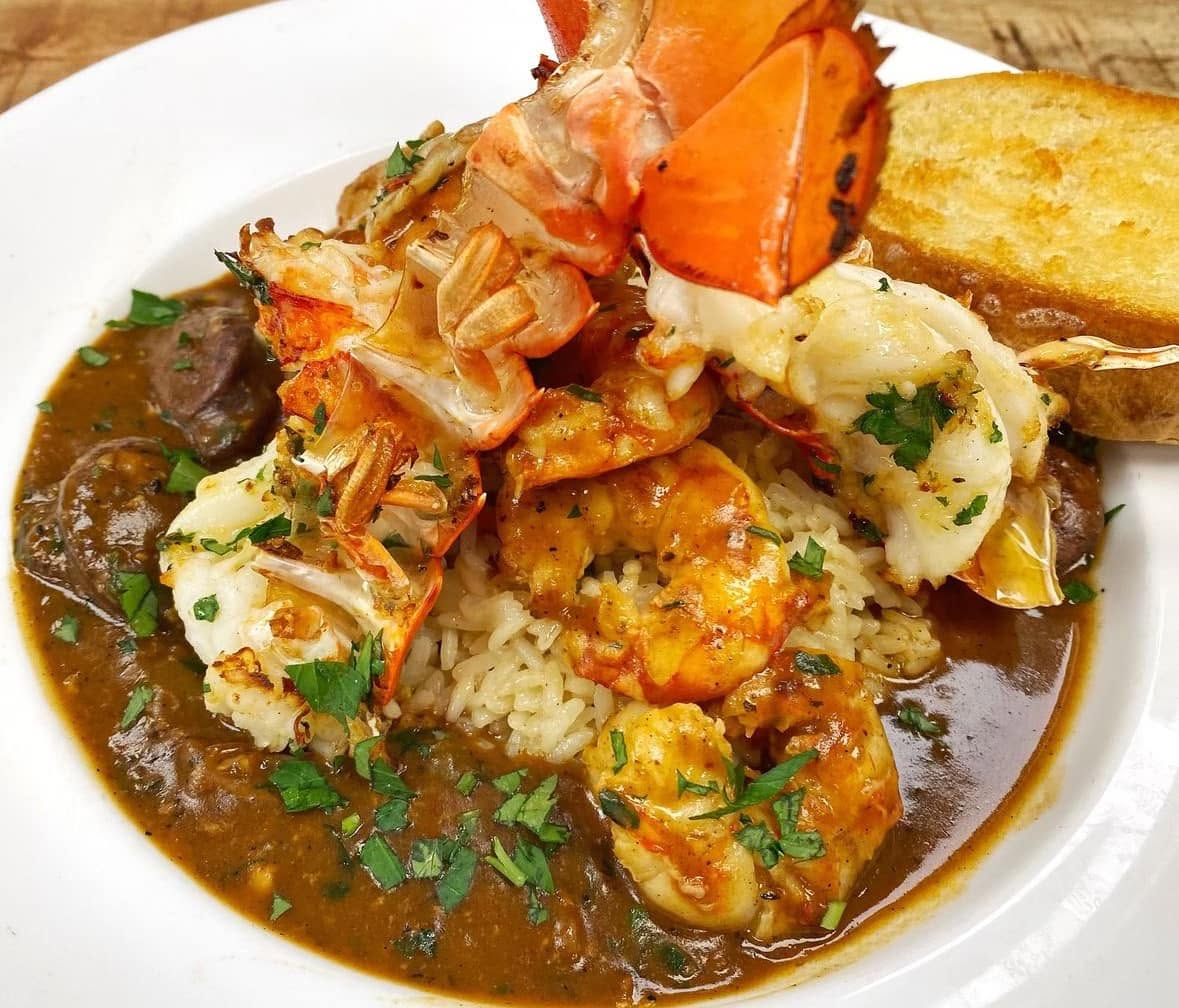 Lobster tail and shrimp over rice in a brown sauce with toasted bread